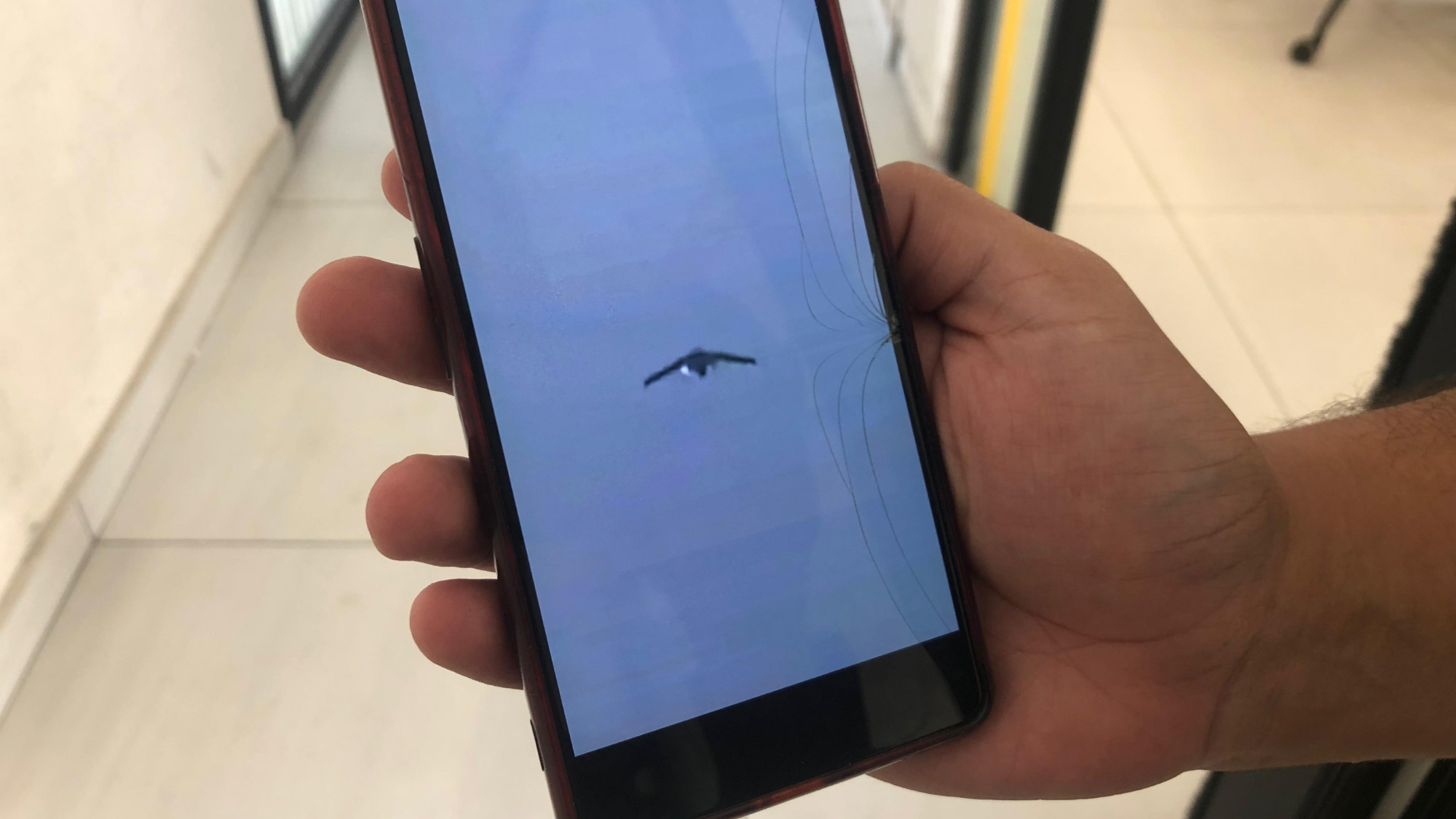 Anas Moeen holds a phone displaying a photo of the drones Israel is using in Gaza to broadcast menacing messages to civilians (Supplied)